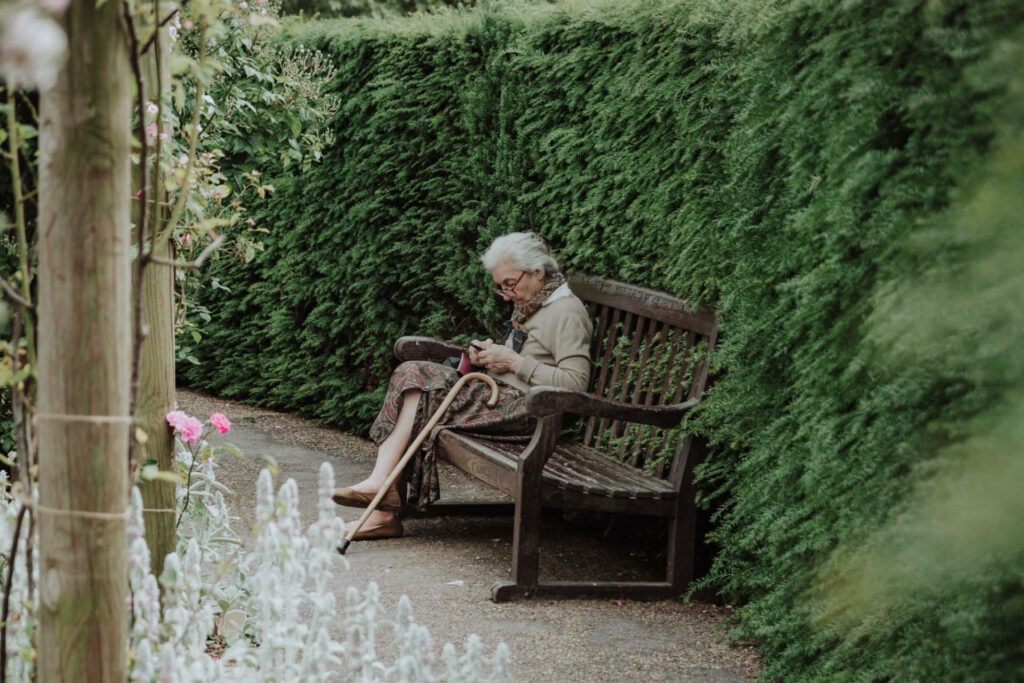 Ältere Dame mit Dekubitus sitzt auf einer Bank