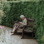 Ältere Dame mit Dekubitus sitzt auf einer Bank