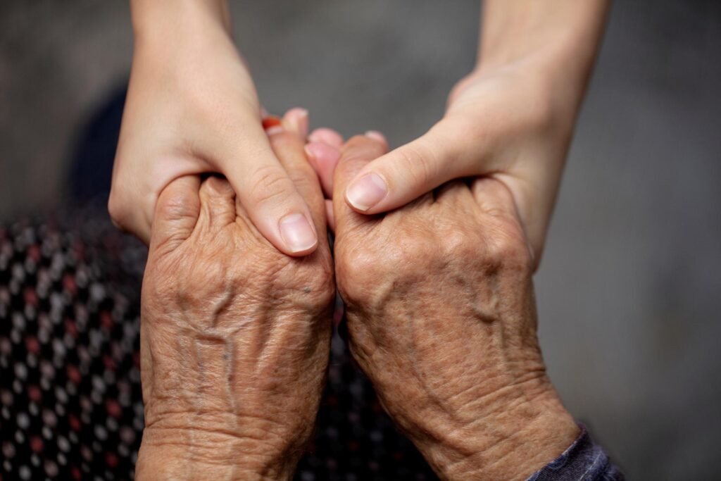 Palliativ Pfleger hält die Hände einer älteren Person